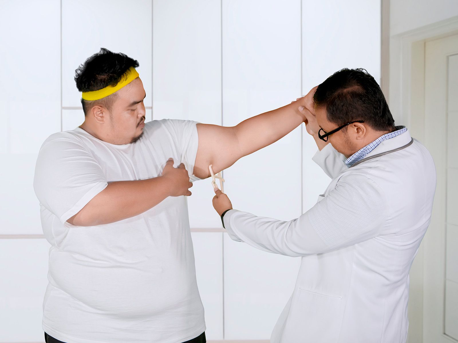 Overweight man getting his blood pressure taken by a doctor